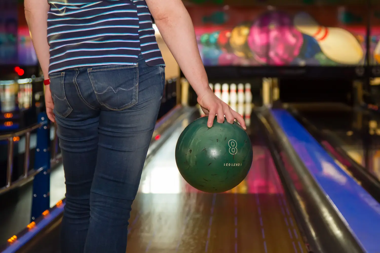 Nahaufnahme einer Frau mit einer Bowlingkugel im Bowlingclub, Rückansicht